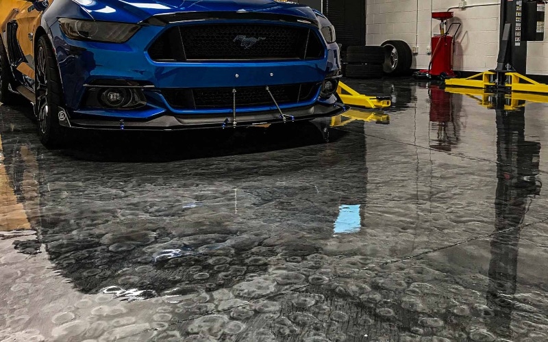 Silver epoxy flooring for repair garage with a blue Ferrari
