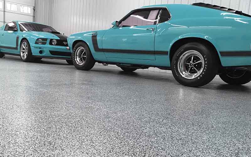 Turquoise muscle cars parked in a custom garage.